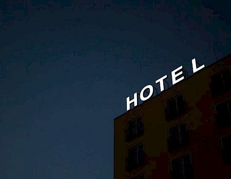 A building with a glowing "HOTEL" sign against a dark sky.
