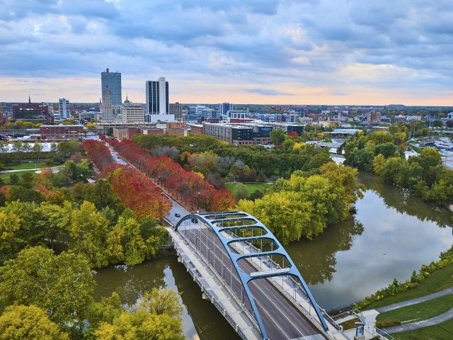 A scenic coastal town with colorful houses, a rocky shoreline, and calm blue water under a bright sky.