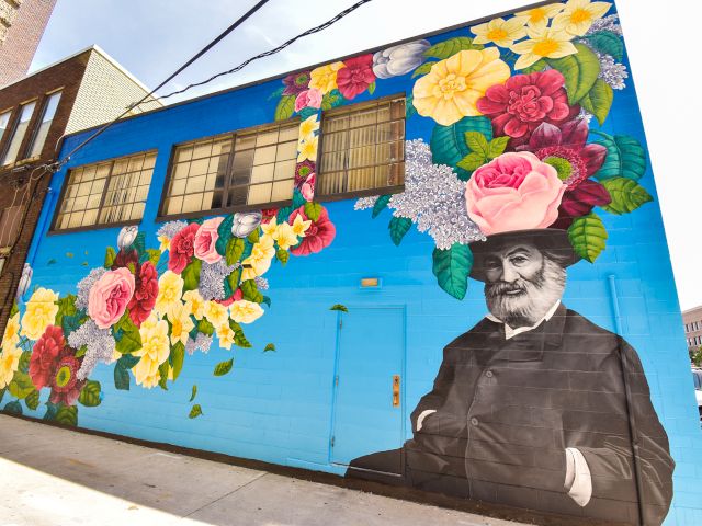 Colorful world map mural on a wall, with a bright blue sky background and decorative border, featuring various continents outlined in vibrant colors.