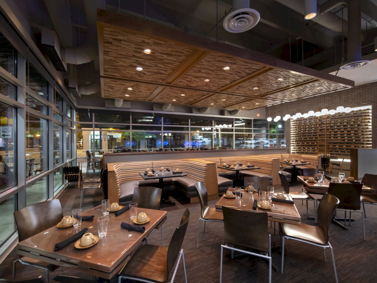 A modern restaurant interior with wooden tables, neatly arranged chairs, and ambient lighting.