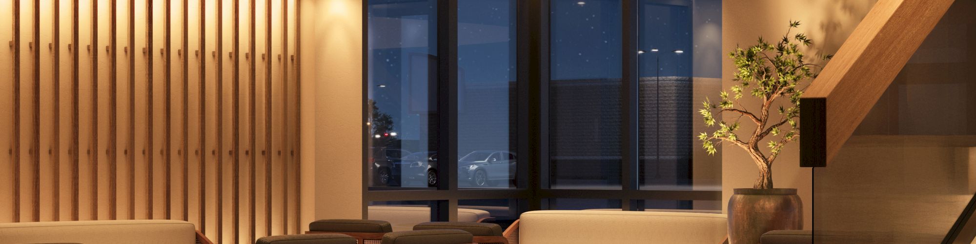 A modern, cozy lounge with warm lighting, featuring sofas, chairs, a round staircase, and large windows overlooking the night view.